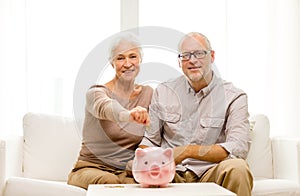 Senior couple with money and piggy bank at home