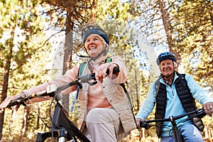 Senior couple mountain biking on a forest trail, low angle