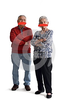Senior couple with mouth covered on white