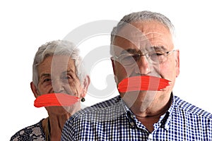 Senior couple with mouth covered on white