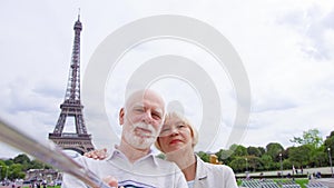 Senior couple near Eiffel Tower doing selfie. Tourist in Europe. Active modern life after retirement