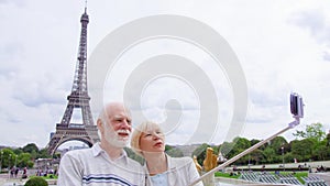 Senior couple near Eiffel Tower doing selfie. Tourist in Europe. Active modern life after retirement