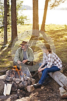 Senior couple near a lake sitting by a camp fire