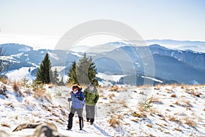 Senior couple with nordic walking poles hiking in snow-covered winter nature.