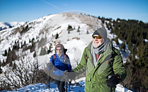 Starší pár s palicami na nordic walking turistiku v zasneženej zimnej prírode.