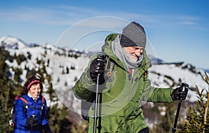 Starší pár s holemi pro nordic walking turistika v zasněžené zimní přírodě.