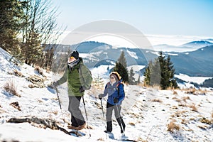 Starší pár s palicami na nordic walking turistiku v zasneženej zimnej prírode.