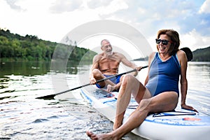 Senior couple paddleboarding on lake in summer. photo