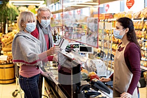 Senior couple paying at cashdesk at supermarket