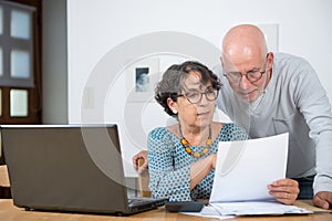 Senior couple paying their bills with laptop at home