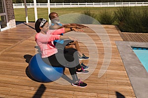 Senior couple performing balancing on exercise ball in the backyard