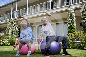 Senior couple performing stretching exercise on fitness ball