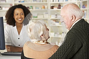 Senior couple in pharmacy with pharmacist photo