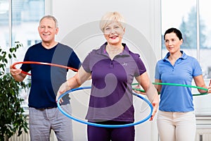 Senior couple in physiotherapy doing exercise with hula hoop