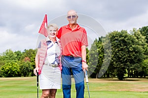 Senior couple playing golf standing on green