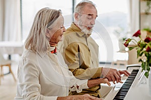 Senior couple playing on piano together at home.