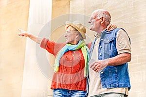 Senior couple pointing a monument during vacation - Active elderly tourist traveling Europe - Concept of  travel lifestyle without