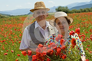 Senior couple on the poppy field enjoying summer