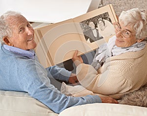 Senior couple, portrait or looking at photo album together, pictures or memories at home, living room or couch. Elderly