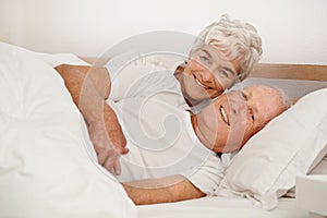 Senior couple, portrait and relaxing in bed, smiling and love in retirement for bonding on weekend. Elderly people