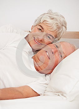 Senior couple, portrait and together in bed, relaxing and love in retirement for bonding on weekend. Elderly people