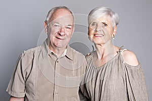 Senior couple posing on studio gray background