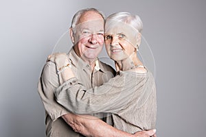 Senior couple posing on studio gray background