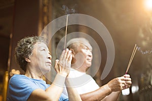 Senior couple praying buddha with incense stick