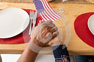 Senior couple praying with hand in hand on dining table at home