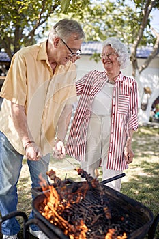 Senior couple preparing barbecue in garden.Elderly man cooking food on the grill