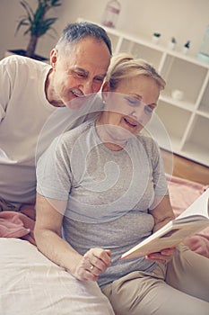 Senior couple reading book in bed.