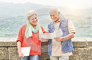 Senior couple reading tourist map inside italian castle outdoor - Mature Husband and wife having fun in romantic vacation- Love