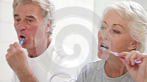 Senior Couple Reflected In Bathroom Mirror Brushing Teeth