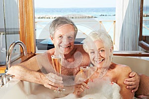 Senior Couple Relaxing In Bath Drinking Champagne Together