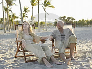 Senior Couple Relaxing On Deckchairs At Beach