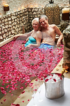 Senior Couple Relaxing In Flower Petal Covered Pool At Spa