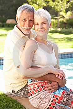 Senior Couple Relaxing By Pool In Garden