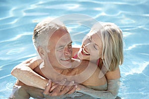 Senior Couple Relaxing In Swimming Pool Together