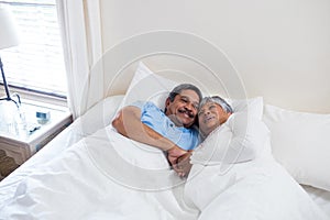 Senior couple relaxing together on bed in bedroom