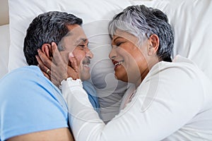 Senior couple relaxing together on bed in bedroom