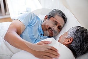 Senior couple relaxing together on bed in bedroom