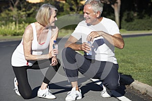 Senior Couple Resting And Drinking Water After Exercise