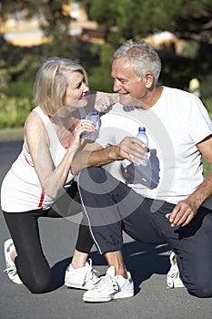 Senior Couple Resting And Drinking Water After Exercise