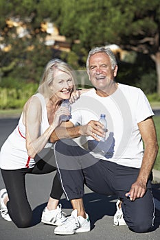 Senior Couple Resting And Drinking Water After Exercise