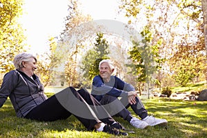 Senior Couple Resting After Exercising In Park Together