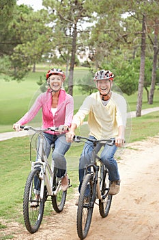 Senior couple riding bicycle in park