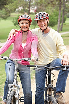 Senior couple riding bicycle in park