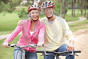 Senior couple riding bicycle in park