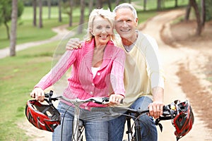 Senior couple riding bicycle in park photo