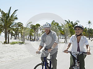 Senior Couple Riding Bicycles On Beach